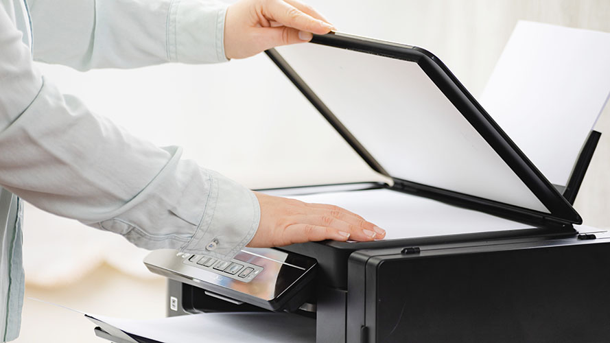 User placing a document into a scanner.